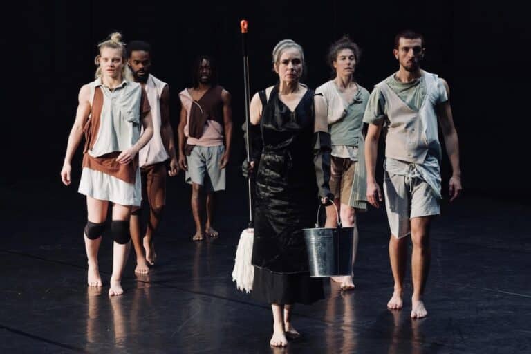 Plusieurs acteurs sur une scène avec un fond et un sol de couleur noire