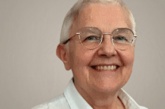 Portrait de Françoise Lempereur souriant devant un mur blanc