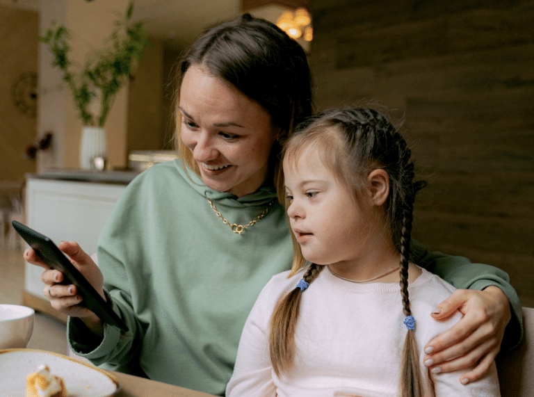 Une femme et une jeune fille porteuse d'un handicap assise l'une à côté de l'autre