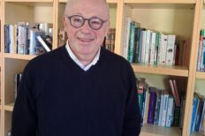 Photo de Christophe Lamfalussy devant une bibliothèque remplie de livres