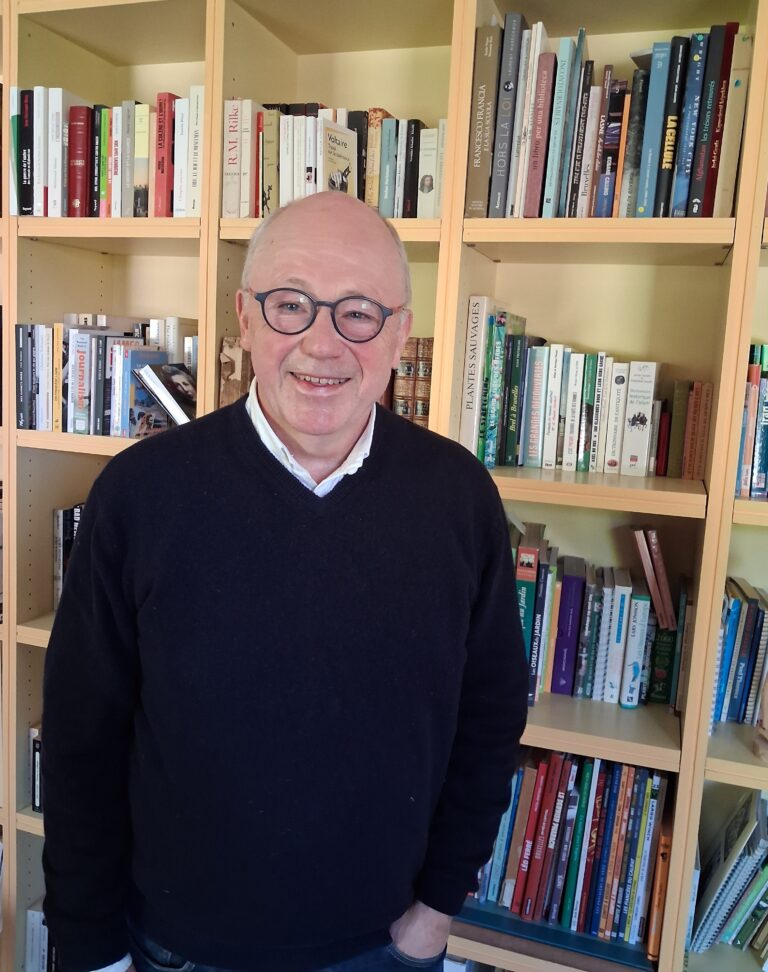 Photo de Christophe Lamfalussy devant une bibliothèque remplie de livres