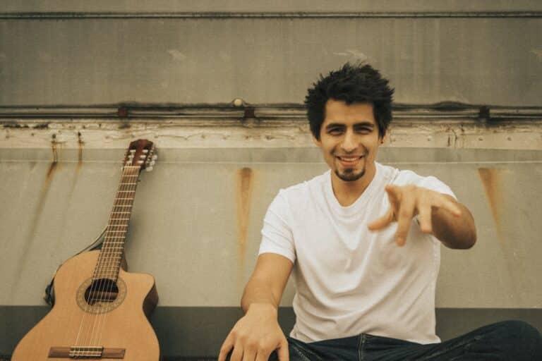 Le chanteur David Mendez assis une guitare à côté de lui