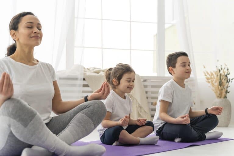 Des personnes faisant du yoga sur un tapis dont deux enfants